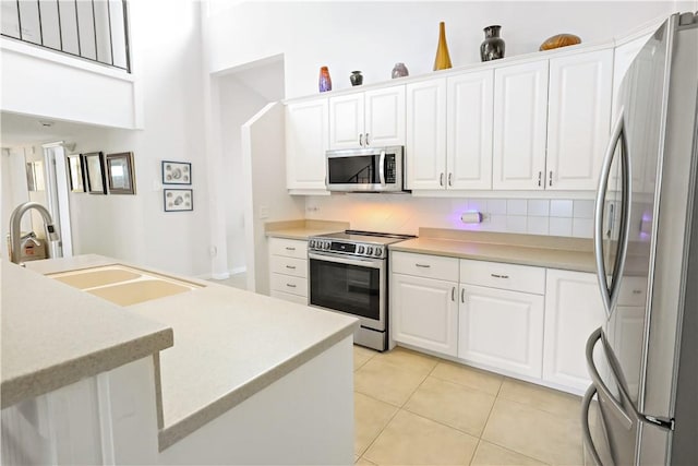 kitchen with sink, light tile patterned flooring, white cabinets, and appliances with stainless steel finishes