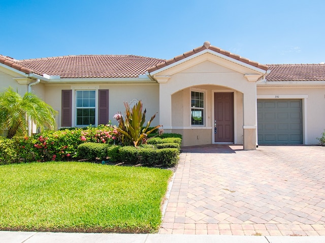 mediterranean / spanish-style home featuring stucco siding, a tile roof, decorative driveway, and a garage