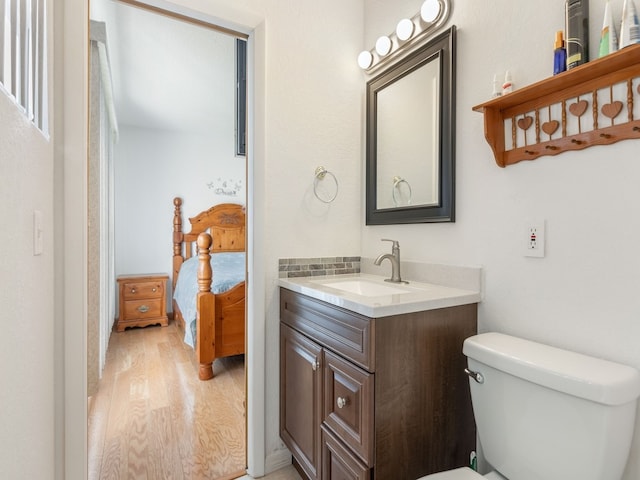 bathroom with hardwood / wood-style flooring, vanity, and toilet