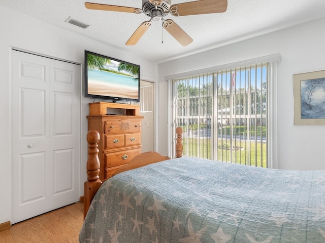 bedroom with light hardwood / wood-style floors, ceiling fan, and a textured ceiling