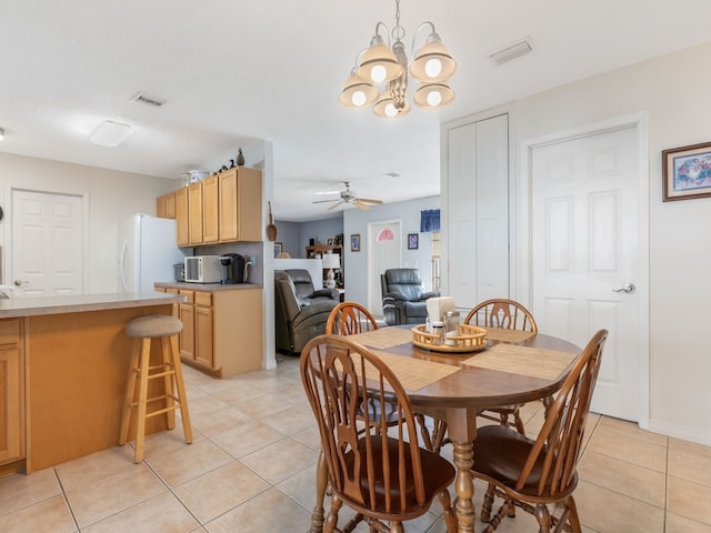 tiled dining area featuring ceiling fan with notable chandelier