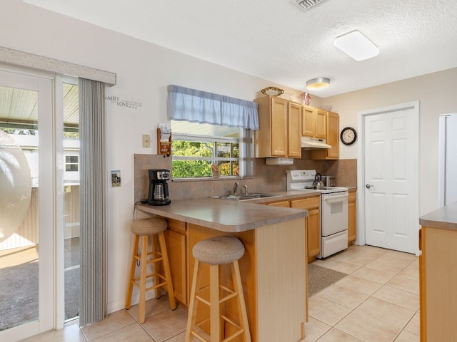 kitchen featuring backsplash, white appliances, light tile patterned floors, and a breakfast bar