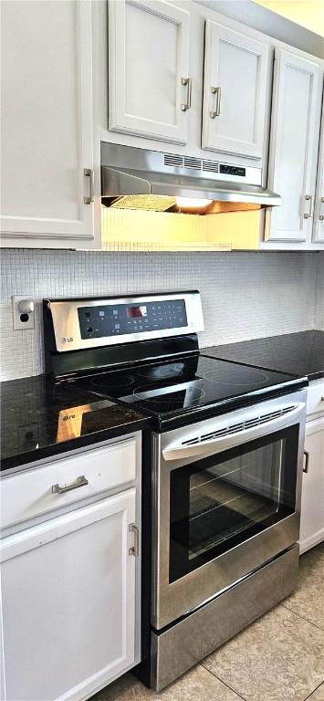 kitchen with dark countertops, electric range, decorative backsplash, white cabinets, and under cabinet range hood