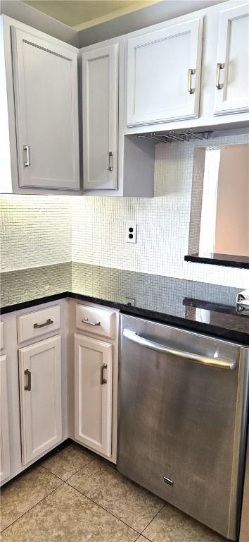 kitchen featuring dark countertops, tasteful backsplash, white cabinets, and stainless steel dishwasher