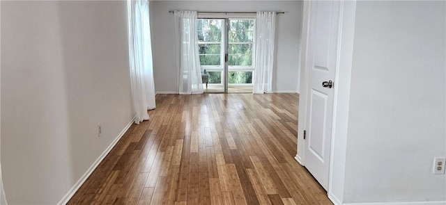 empty room with baseboards, light wood-type flooring, and a healthy amount of sunlight