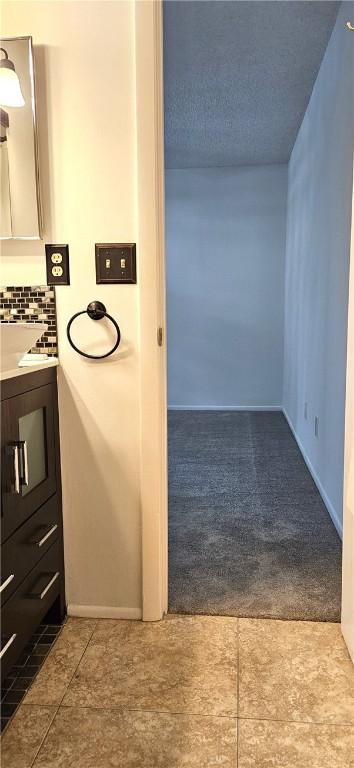 bathroom with tile patterned flooring, backsplash, vanity, and a textured ceiling