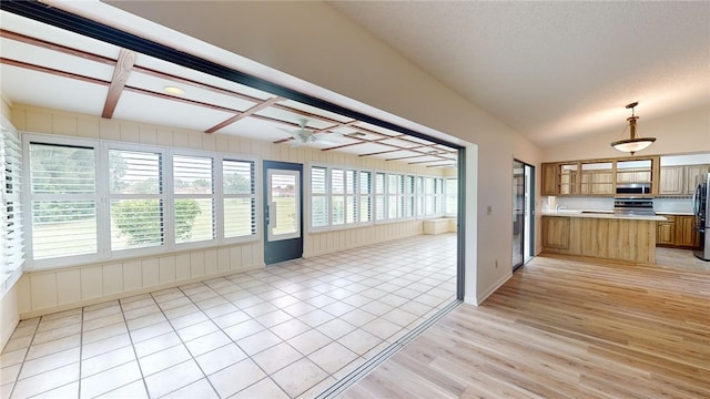 interior space featuring stainless steel appliances, light wood-type flooring, a textured ceiling, hanging light fixtures, and ceiling fan