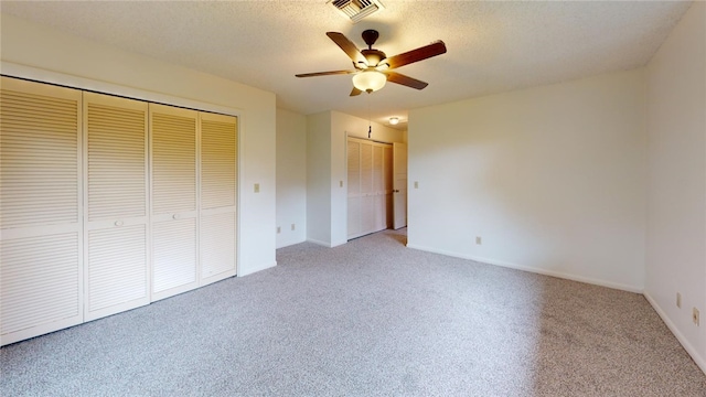 unfurnished bedroom featuring a textured ceiling, light colored carpet, and ceiling fan