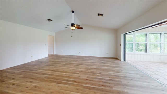 spare room featuring light wood-type flooring, lofted ceiling, a textured ceiling, and ceiling fan