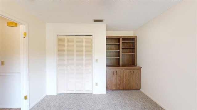 unfurnished bedroom with light carpet, a textured ceiling, and a closet