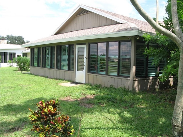 585 W Forest Trl, Vero Beach, FL 32962 - view of side of home with a shingled roof, a sunroom, and a yard
