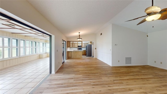 interior space with light hardwood / wood-style floors, ceiling fan, a textured ceiling, and lofted ceiling