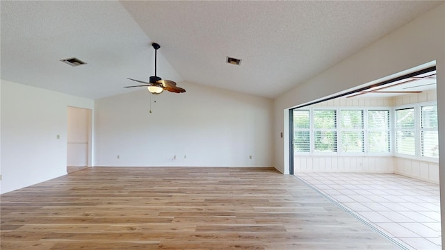 unfurnished room with light wood-type flooring, vaulted ceiling, ceiling fan, and a textured ceiling