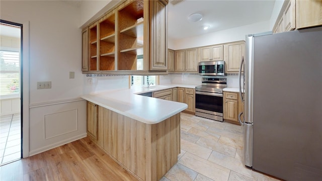 kitchen with stainless steel appliances, light hardwood / wood-style floors, sink, kitchen peninsula, and light brown cabinets