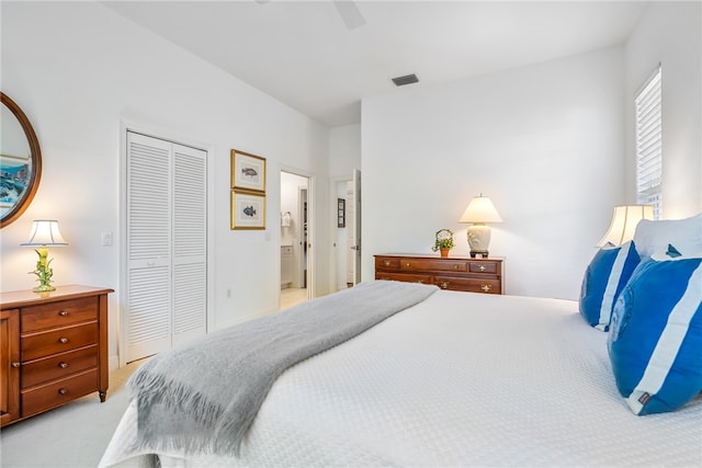 bedroom with ceiling fan, light colored carpet, ensuite bath, and a closet