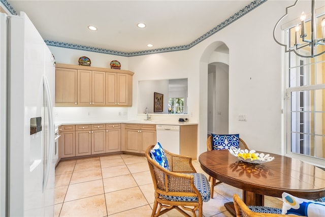 kitchen with light brown cabinetry, white appliances, an inviting chandelier, and light tile patterned floors