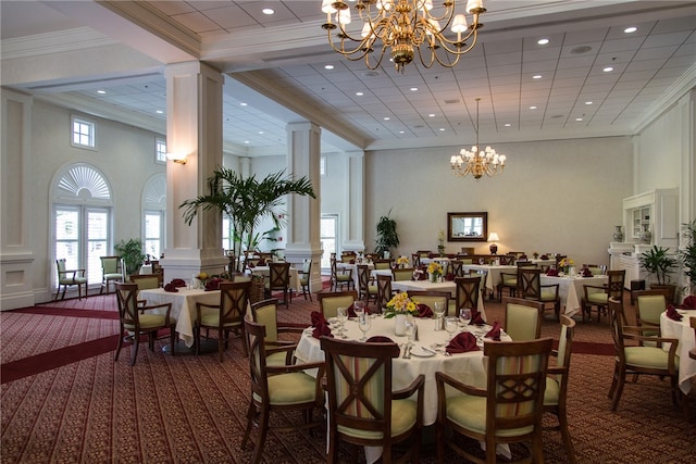 carpeted dining space with ornate columns, crown molding, a towering ceiling, and an inviting chandelier