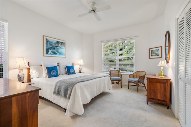 bedroom with a closet, ceiling fan, and light colored carpet