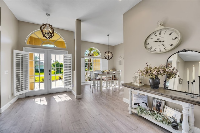 entryway with light wood-type flooring, a chandelier, and french doors