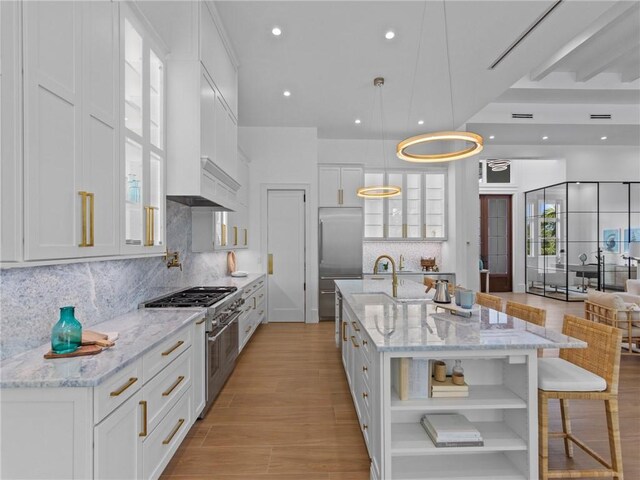 kitchen with white cabinets, glass insert cabinets, open shelves, high quality appliances, and backsplash