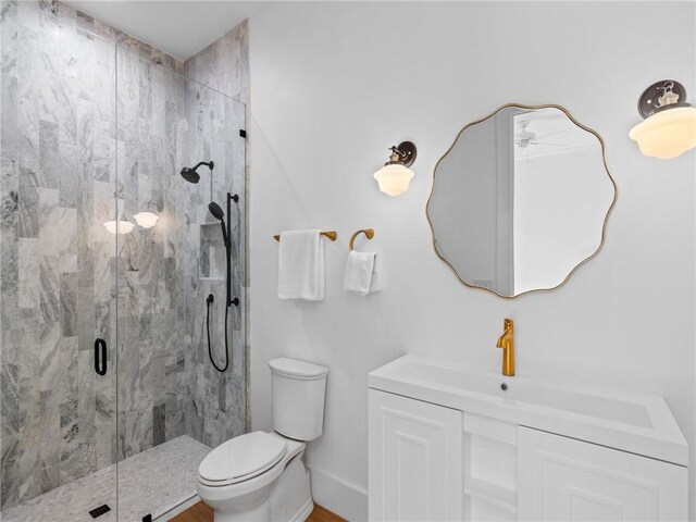 bathroom featuring a marble finish shower, baseboards, toilet, and vanity