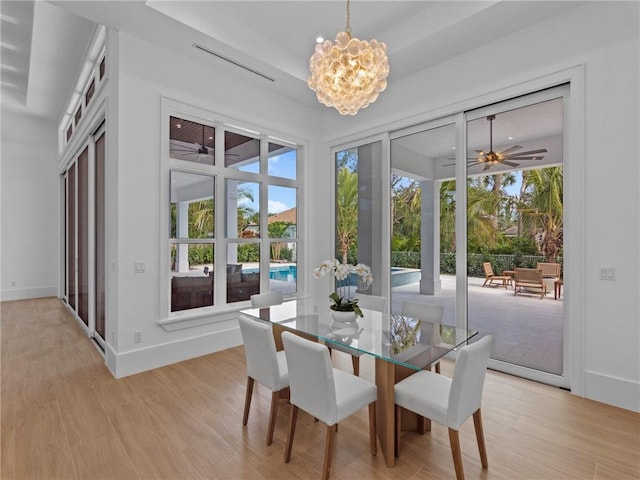 dining room featuring baseboards, light wood-type flooring, and ceiling fan with notable chandelier