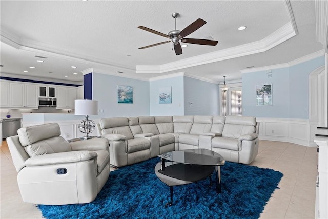 728 S Ocracoke Sq SW, Vero Beach, FL 32968 - living area with a raised ceiling, crown molding, a ceiling fan, a decorative wall, and a wainscoted wall