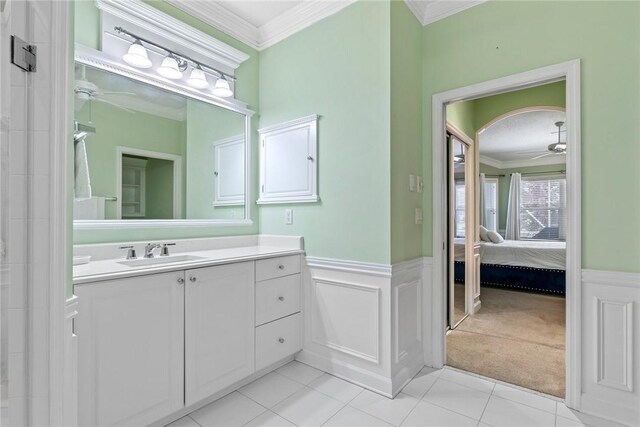 728 S Ocracoke Sq SW, Vero Beach, FL 32968 - ensuite bathroom with a ceiling fan, crown molding, vanity, a wainscoted wall, and tile patterned flooring