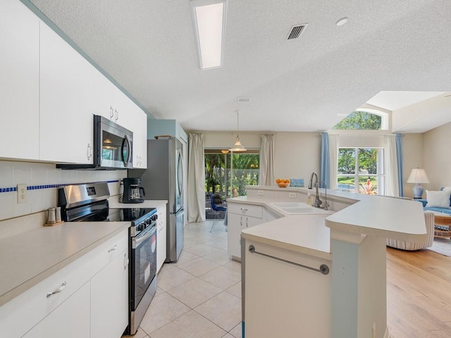 kitchen featuring stainless steel appliances, light countertops, a sink, and plenty of natural light