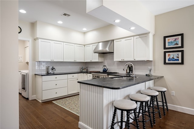 2139 Via Fuentes St Unit 2139, Vero Beach, FL 32963 - kitchen with wall chimney exhaust hood, a peninsula, dark wood finished floors, tasteful backsplash, and recessed lighting