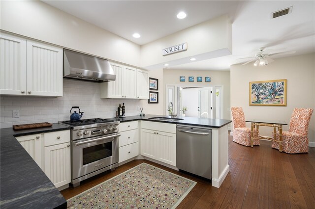 2139 Via Fuentes St Unit 2139, Vero Beach, FL 32963 - kitchen featuring appliances with stainless steel finishes, wall chimney exhaust hood, a peninsula, dark countertops, and backsplash