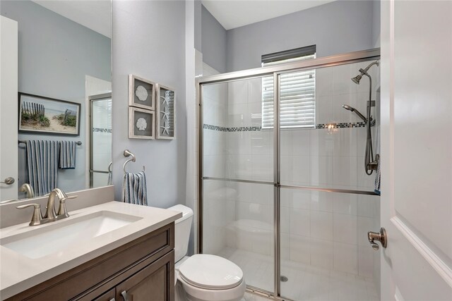 bathroom featuring vanity, toilet, and a shower with shower door