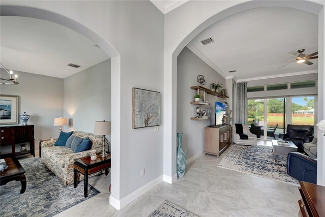 living room with ceiling fan with notable chandelier and crown molding