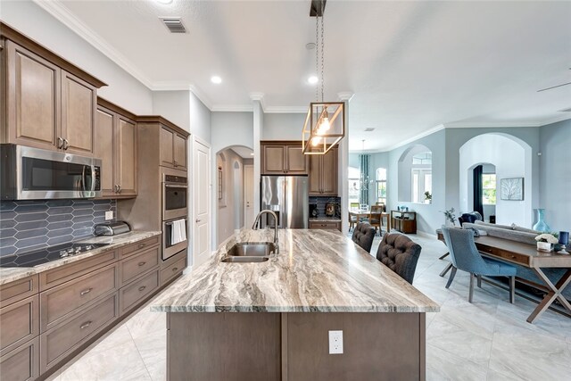 kitchen featuring stainless steel appliances, sink, a spacious island, and decorative light fixtures