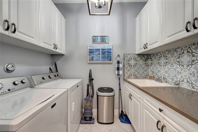 clothes washing area featuring light tile patterned floors, cabinets, an inviting chandelier, sink, and washing machine and clothes dryer