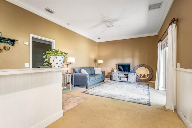 living area featuring crown molding, a ceiling fan, visible vents, and light colored carpet