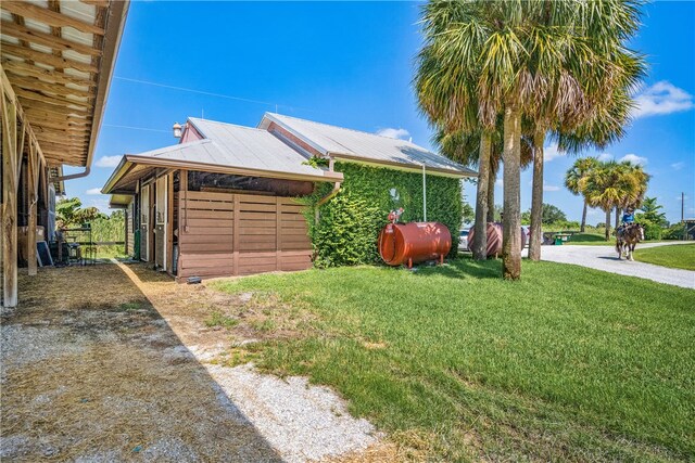 view of side of property with metal roof, a lawn, and heating fuel