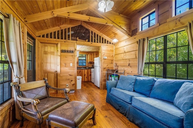 living room featuring vaulted ceiling with beams, light wood finished floors, wood walls, and wooden ceiling