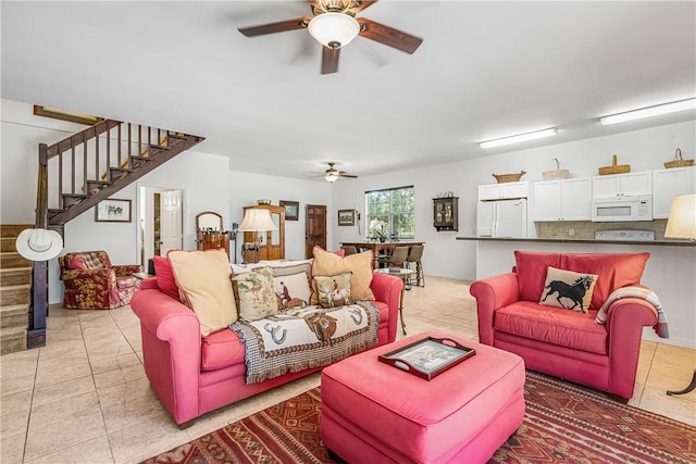 living area with ceiling fan, stairs, and light tile patterned flooring