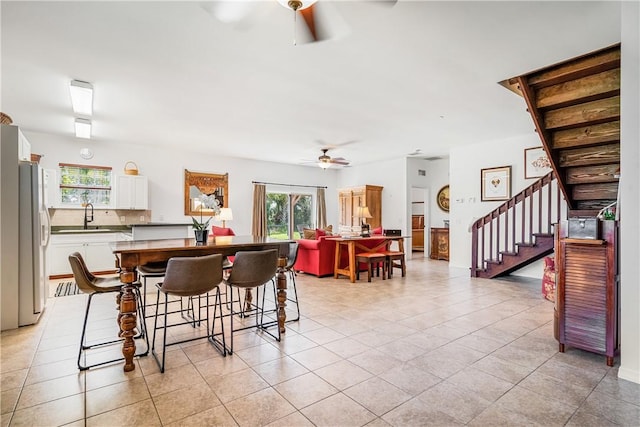 dining area with ceiling fan, light tile patterned floors, and stairway