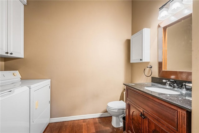 bathroom featuring toilet, vanity, separate washer and dryer, wood finished floors, and baseboards