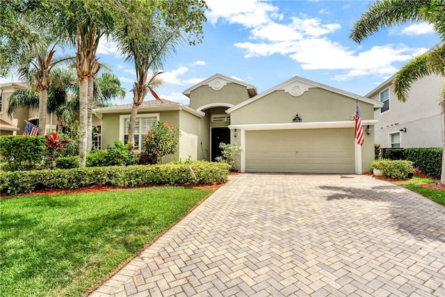 view of front of home with decorative driveway, a garage, a front lawn, and stucco siding