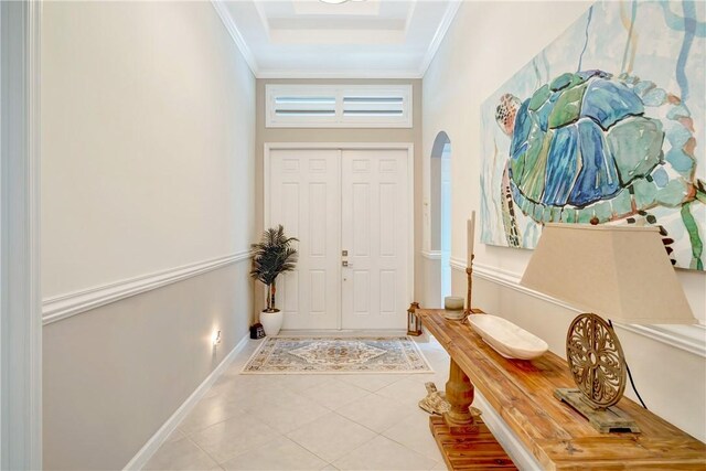 tiled entryway featuring arched walkways, baseboards, and ornamental molding