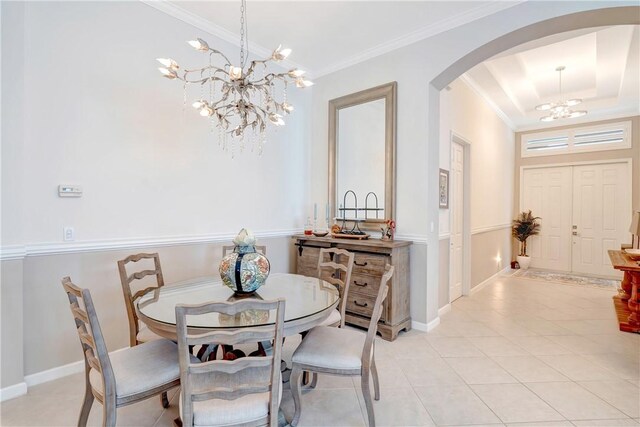 dining area with an inviting chandelier, crown molding, light tile patterned flooring, a tray ceiling, and arched walkways