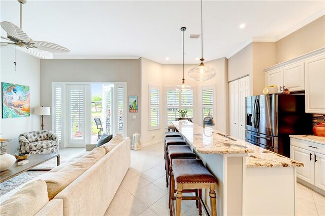 kitchen featuring stainless steel refrigerator with ice dispenser, open floor plan, light tile patterned floors, and a wealth of natural light