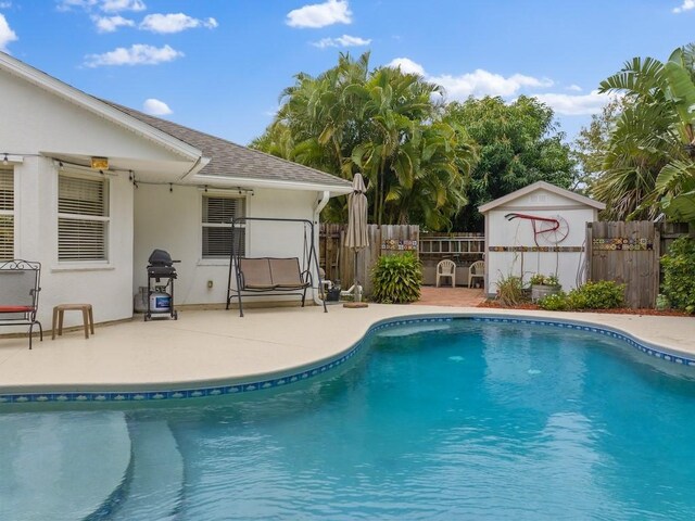 view of swimming pool featuring grilling area, an outdoor structure, and a patio area