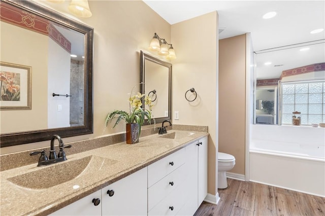 bathroom with a tub to relax in, toilet, hardwood / wood-style floors, and vanity