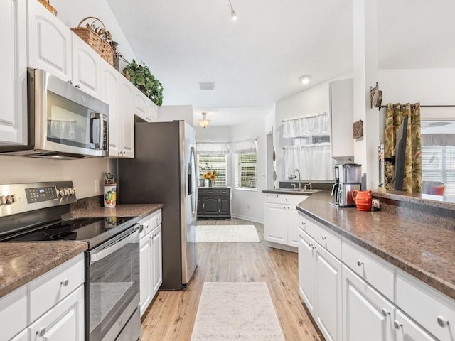 kitchen featuring sink, stainless steel appliances, white cabinets, and light wood-type flooring