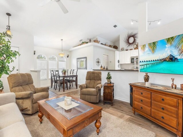 living room with vaulted ceiling, ceiling fan, and light wood-type flooring