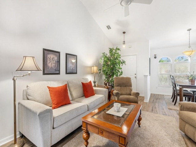 living room with ceiling fan, vaulted ceiling, and light wood-type flooring